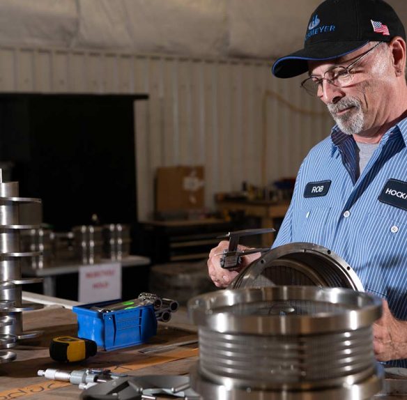 An employee of Hockmeyer Equipment Corporation employee evaluating custom machine parts.